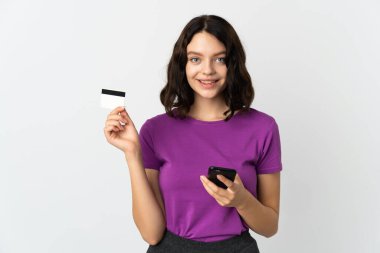 Genç Ukraynalı kız, beyaz arka planda izole edilmiş cep telefonuyla kredi kartıyla alışveriş yapıyor.