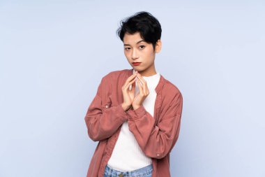 Soyutlanmış mavi arka plan entrikaları çeviren genç bir Asyalı kız.