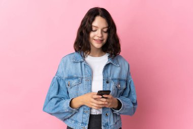 Pembe arka planda izole edilmiş genç Ukraynalı kız cep telefonuyla bir mesaj gönderiyor.