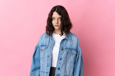 Genç Ukraynalı kız üzgün bir ifadeyle pembe arka planda izole edilmiş.