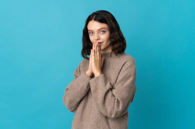 Mavi arka planda izole edilmiş genç Ukraynalı kız avuç içlerini bir arada tutuyor. İnsan bir şey ister.