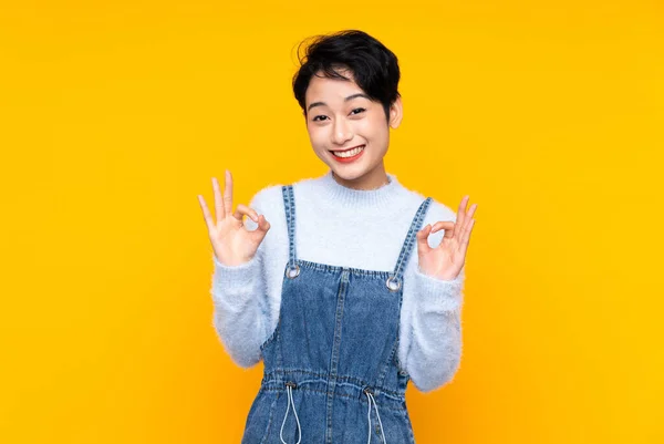 Junge Asiatische Mädchen Overalls Über Isoliertem Gelben Hintergrund Zeigen Ein — Stockfoto