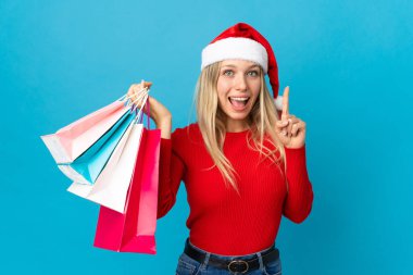 Noel şapkalı kadın mavi arka planda izole edilmiş bir şey alacak. Harika bir fikre işaret ediyor.