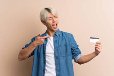 Soyutlanmış geçmişi olan genç bir Asyalı kredi kartı tutuyor.