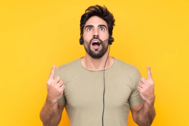 Tele pazarlamacı, izole edilmiş sarı arka plan üzerinde çalışan bir kulaklıkla işaret parmağı ile harika bir fikir.