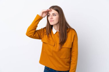 İzole edilmiş beyaz arka planı olan genç bir kadın bir şeye bakmak için çok uzaklara bakıyor.