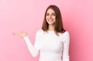 İzole edilmiş pembe arka planı olan genç bir kadın bir ilan vermek için fotokopi cihazını avucunun içinde tutuyor.