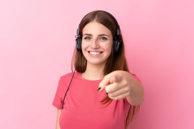 Soyutlanmış pembe arka plan müzik dinleyen ve ön tarafı gösteren genç bir kadın.