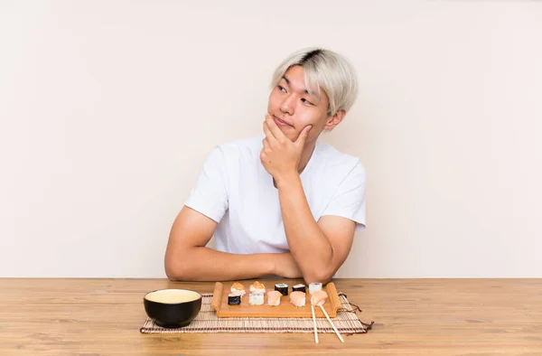 Joven Asiático Hombre Con Sushi Una Mesa Pensando Una Idea — Foto de Stock