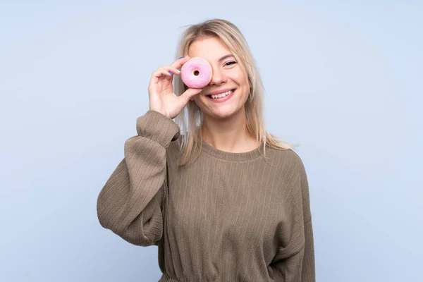 Jovem Loira Sobre Isolado Fundo Azul Segurando Donut Feliz — Fotografia de Stock