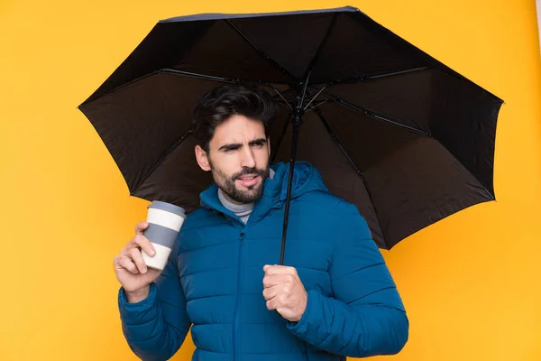 孤立した黄色の背景に傘を持っている男 — ストック写真