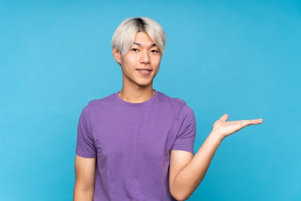 Jovem Asiático Homem Sobre Isolado Azul Fundo Segurando Copyspace Imaginário — Fotografia de Stock