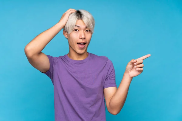 Jovem Asiático Homem Sobre Isolado Azul Fundo Surpreso Apontando Dedo — Fotografia de Stock