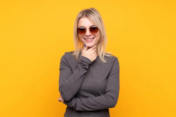 Mujer Rubia Joven Sobre Fondo Amarillo Aislado Con Gafas Sonriendo — Foto de Stock