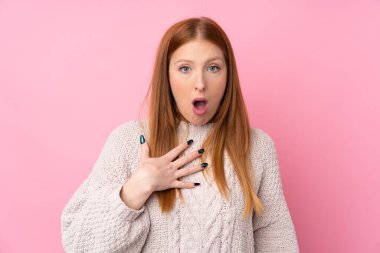 Genç, kızıl saçlı, soyutlanmış pembe arka plan. Şaşırmış ve şaşırmış.