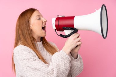 Soyutlanmış pembe arka planda genç bir kızıl kadın megafondan bağırıyor.