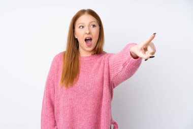 İzole edilmiş beyaz arka planı olan pembe kazaklı genç kızıl kadın.