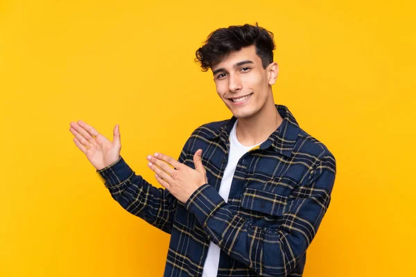 Mladý Argentinský Muž Přes Izolované Žluté Pozadí Natahuje Ruce Stranu — Stock fotografie