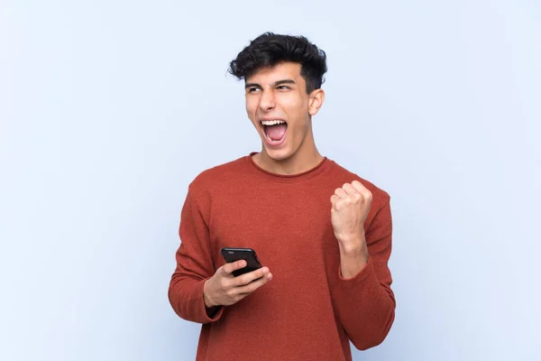 Mladý Argentinský Muž Přes Izolované Modré Pozadí Telefonem Vítězné Pozici — Stock fotografie