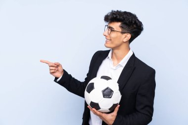 İzole edilmiş mavi arkaplan üzerinde Arjantin Futbol koçu bir ürün sunmak için kenarı işaret ediyor