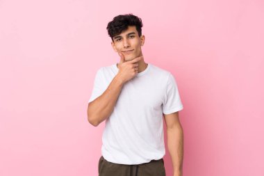 Arjantinli genç adam soyutlanmış pembe arka planda gülüyor