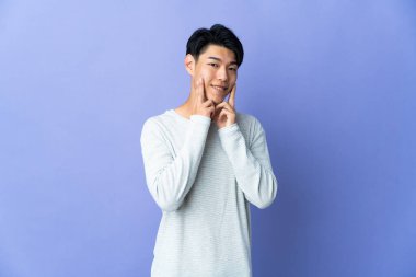 Mor arka planda izole edilmiş genç bir Çinli mutlu ve hoş bir ifadeyle gülümsüyor.