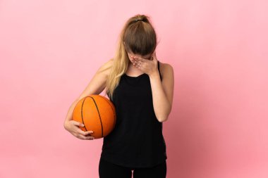 Basketbol oynayan genç sarışın kadın, pembe arka planda izole edilmiş, yorgun ve hasta bir ifadeyle.