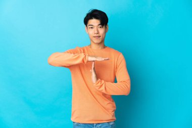 Genç Çinli bir adam mavi arka planda izole edilmiş.
