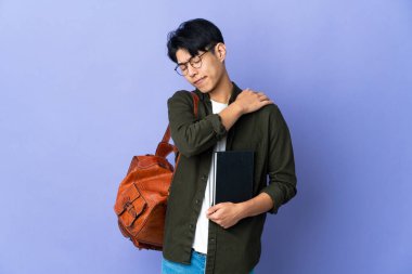 Mor arka planda izole edilmiş genç bir bayan omuz ağrısından muzdarip.