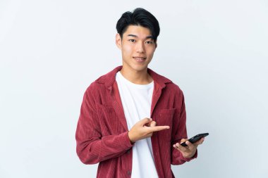 Genç Çinli adam beyaz arka planda cep telefonu kullanarak izole edilmiş.