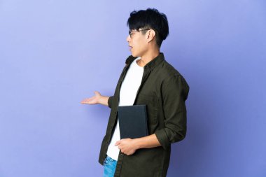 Mor arka planda izole edilmiş genç bir kız öğrenci. Sürpriz bir ifadeyle yan tarafa bakıyor.