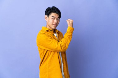 Mor arka planda izole edilmiş genç bir Çinli güçlü bir jest yapıyor.