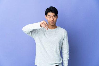 Mor arka planda izole edilmiş genç bir Çinli başparmağının negatif ifadesini gösteriyor.