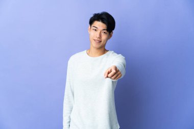 Mor arka planda izole edilmiş genç bir Çinli, mutlu bir ifadeyle öne bakıyor.