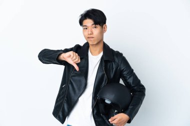 Beyaz arka planda izole edilmiş motosiklet kasklı Çinli bir adam, olumsuz ifade ile baş parmağını aşağı gösteriyor.