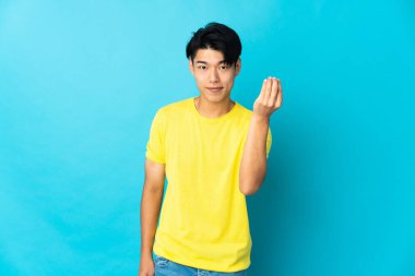 Mavi arka planda izole edilmiş genç bir Çinli İtalyan jesti yapıyor.