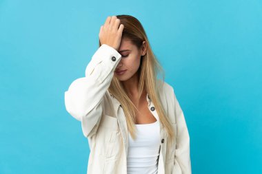 Mavi arka planda başağrısı olan genç sarışın kadın.