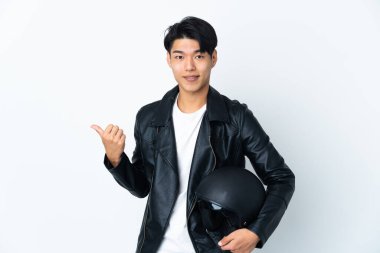 Beyaz arka planda izole edilmiş motosiklet kasklı Çinli bir adam bir ürün sunmak için kenarı işaret ediyor.