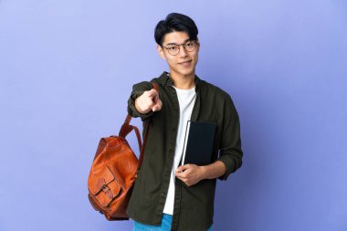 Mor arka planda izole edilmiş genç bir bayan mutlu bir ifadeyle ön tarafı gösteriyor.