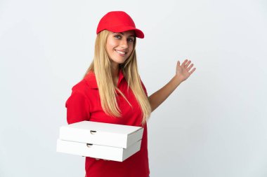 Pizzacı kadın beyaz arka planda izole edilmiş bir pizza tutuyor. Davet etmek için ellerini yana uzatıyor.