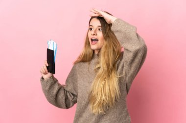 Gezgin kadın pembe arka planda izole edilmiş bir bavul tutuyor. Pasaport ve uçak biletleriyle uzaklarda bir yere bakıyor.