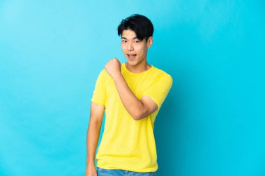 Mavi arka planda izole edilmiş genç bir Çinli zaferi kutluyor.