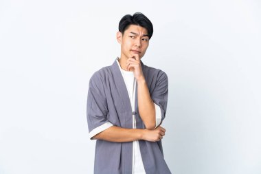 Genç Çinli bir adam beyaz arka planda izole edilmiş. Şüpheleri ve düşünceleri var.