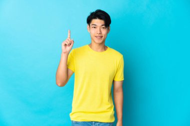 Mavi arka planda izole edilmiş genç bir Çinli harika bir fikre işaret ediyor.