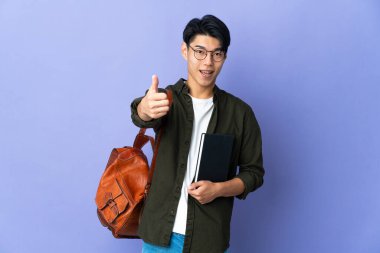 Mor arka planda izole edilmiş genç bir bayan. Başparmakları havada. Çünkü iyi bir şey oldu.