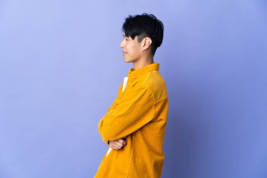 Genç Çinli adam mor arka planda izole edildi.