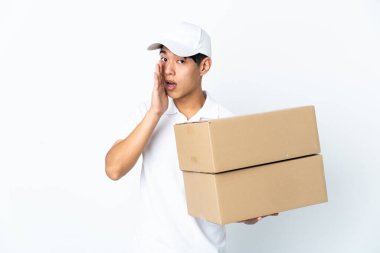 Beyaz arka planda izole edilmiş Çinli bir adam. Yan tarafa bakarken sürpriz bir jest yaparak bir şeyler fısıldıyor.