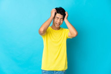 Genç Çinli adam mavi arka planda yalnız gülüyor.