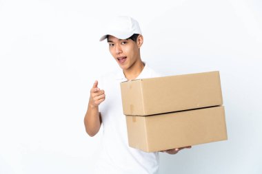 Beyaz arka planda izole edilmiş Çinli bir teslimat önü işaret ediyor ve gülümsüyor.