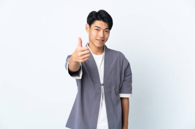 Genç Çinli adam beyaz arka planda izole edildi. Başparmakları havada çünkü iyi bir şey oldu.